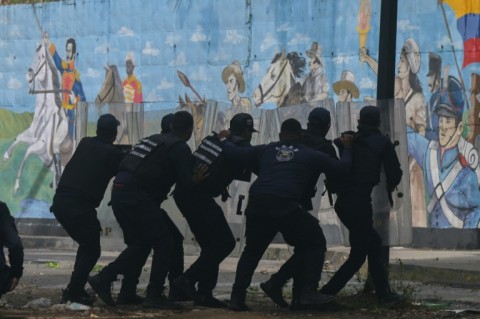 Police officers take cover from demonstrators during an anti-Maduro protest in Caracas on July 29, 2024 