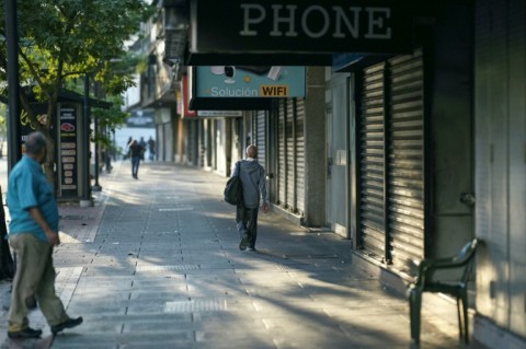 People walk in front of closed shops in Caracas on August 30 after a blackout hit Venezuela