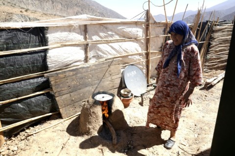 A woman burns wood for cooking in her temporary shelter in Tiniskt, where she awaits reconstruction on her destroyed home