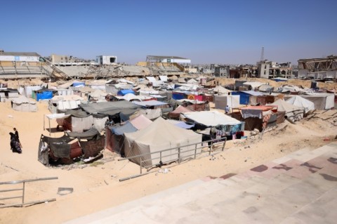 Displaced Palestinians walks next to tents at a makeshift camp for the displaced in Khan Yunis in the southern Gaza Strip