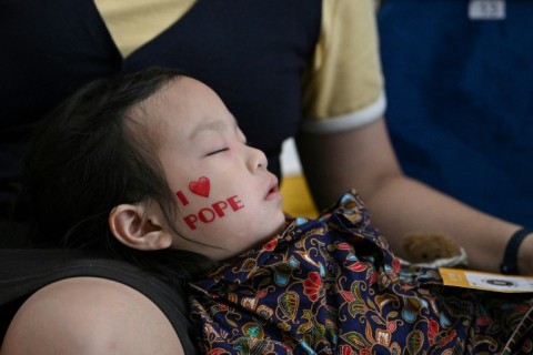 A child falls asleep as Catholic faithful wait to attend the holy mass led by Pope Francis at the National Stadium in Singapore on September 12, 2024