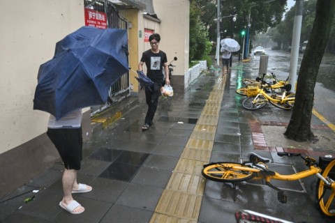 People walk past fallen bicycles amid strong winds and rain from Typhoon Bebinca