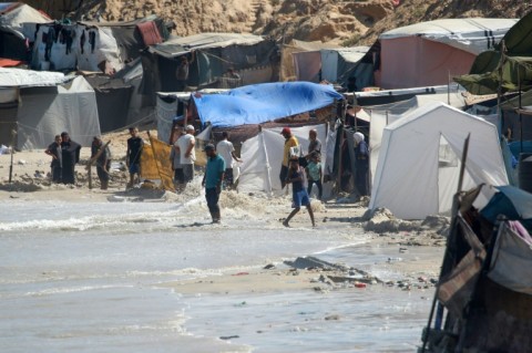 Displaced Palestinians gather near tents that flooded with sea water because of the high tide combined with windy weather along the shore of Khan Yunis in southern Gaza