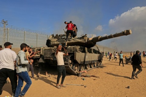 Palestinians seize an Israeli Merkava battle tank after crossing the border fence from Khan Yunis in southern Gaza on October 7, 2023