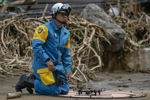 A police officer works with a drone to look for missing people along the Tsukada river