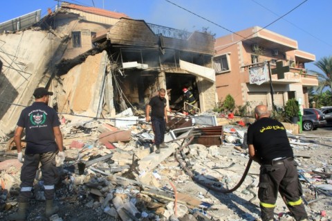 Lebanese emergency services inspect the rubble of a village pharmacy hit by an overnight Israeli strike