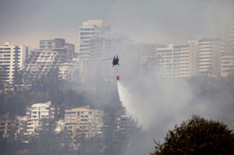 A helicopter sprays water over a bushfire on a hill in Quito on September 25, 2024