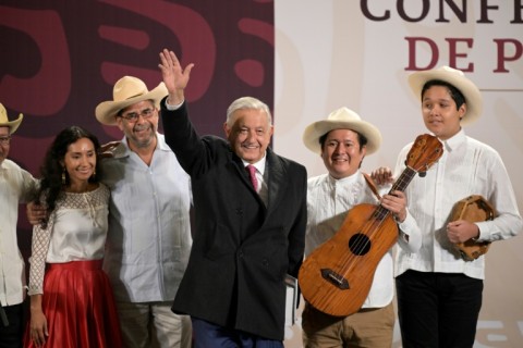 Outgoing Mexican President Andres Manuel Lopez Obrador waves next to members of the musical group Mono Blanco at the end of his last daily news conference at the National Palace