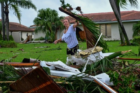 A woman collects debris caused by a hurricane-fueled tornado in Cocoa Beach, Florida