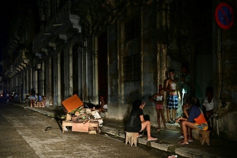 Cubans chat at night on a street during a nationwide blackout in Havana