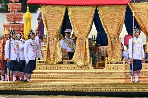 Thailand's King Maha Vajiralongkorn (C) sits in his royal barge during the procession along the Chao Phraya River in Bangkok