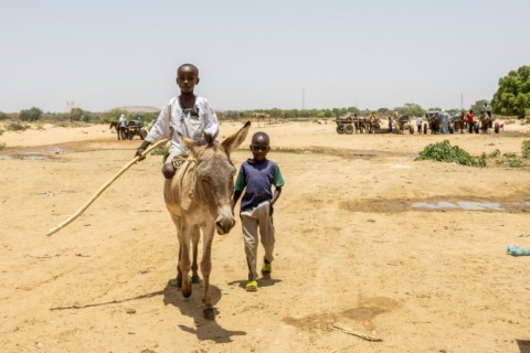 Two young boys cross the border between Chad and Sudan at the Koufroun refugee camp