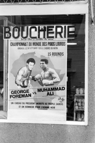 A poster in a butcher's shop window advertises The Rumble in the Jungle