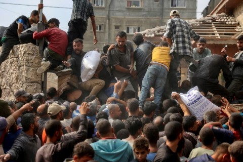 People scramble to receive sacks of flour at a United Nations Relief and Works Agency (UNRWA) aid distribution centre in Deir el-Balah, central Gaza