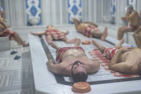 Lying on a heated marble slab, people relax inside a modern hamma