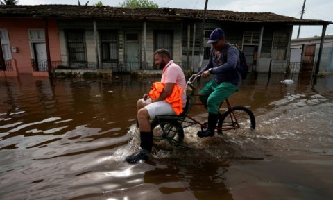 Men ride a bicycle through flooded waters after the passage of Hurricane Rafael in Batabano in western Cuba 