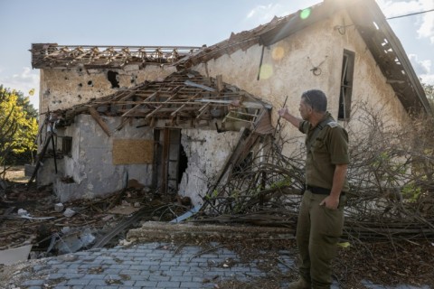 An Israeli soldier points at a house hit by Hezbollah rocket fire in the deserted northern Israeli town of Metula