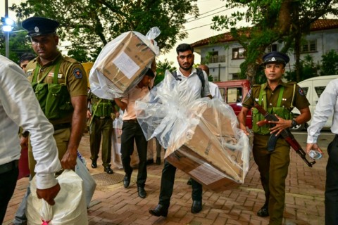 Election officials and security personnel transport sealed ballot boxes to a counting centre