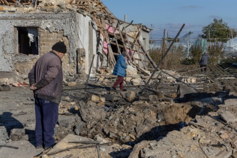 A local resident inspects a crater in the courtyard of a destroyed building following a missile attack at an undisclosed location in Odesa region on November 17