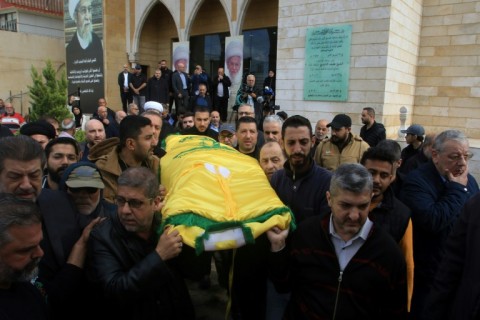 Mourners carry the body of Hezbollah's spokesman Mohammed Afif, draped with the militant group's yellow flag, during his funeral in Sidon