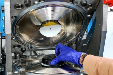 A hot PVC puck is placed in a vinyl stamper to make a record