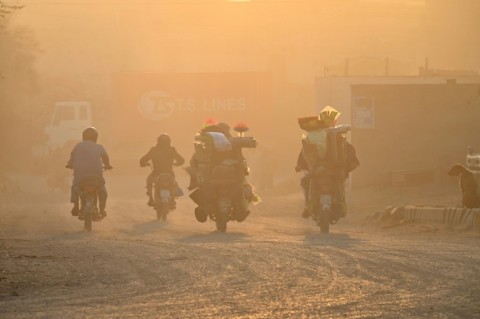 Commuters ride along a street engulfed in smog in Lahore 