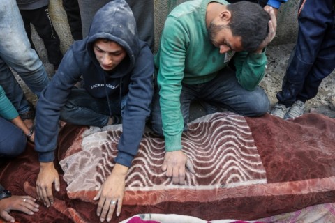 Men mourn over the bodies of victims of a strike near Gaza City, more than 13 months into the Israel-Hamas war