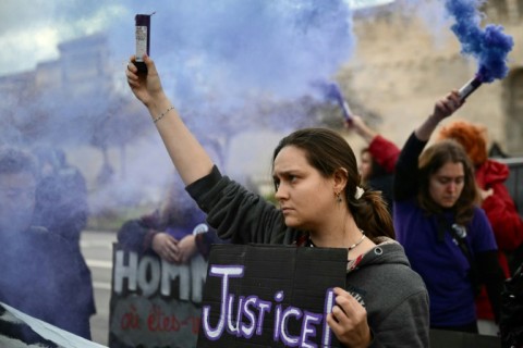 A protester holds a flare and a placard reading "Justice" during a demonstration organised by the "Les Amazones d'Avignon" feminist collective in support of Gisele Pelicot 