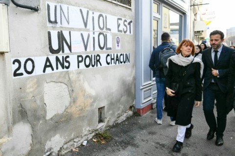 Gisele Pelicot (2nd R) walks past posters reading "Rape is rape. 20 years for every one of them" outside the Avignon courthouse