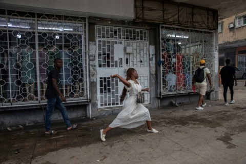 A woman throws a stone during clashes with riot police in Maputo