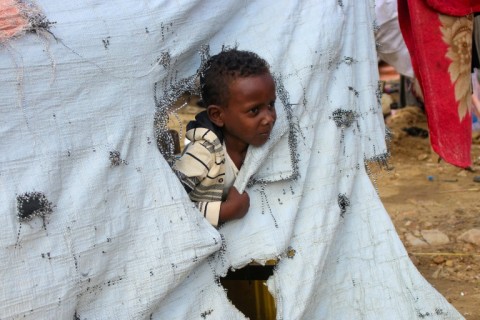 A child looks on from inside his tent at a makeshift camp for displaced people in Yemen's northwestern Abs region