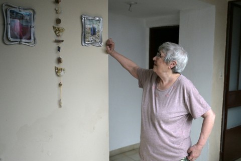 Alicia Ceresoli looks at portraits of her grandchildren at her home in Villa Adelina, on the outskirts of Buenos Aires