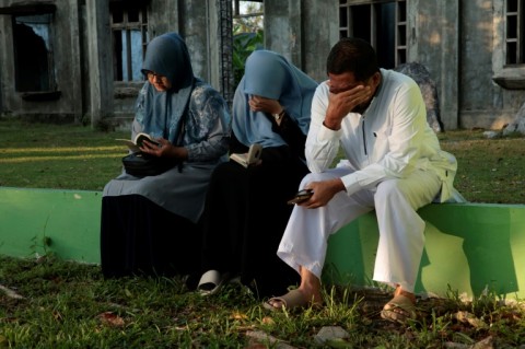 Mourners react as they gather at a mass grave in Indonesia's Aceh Province 20 years after the tsunami