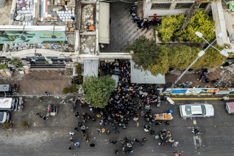 Men wait outside a transitional government centre to hand over small arms and register former soldiers, police members and civilians in Damascus