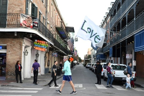 A man runs with a 'Love' flag down Bourbon Street