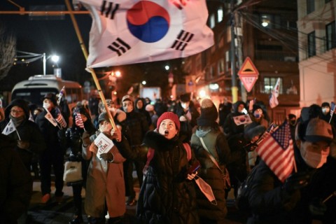 A woman waves South Korea's flag during a rally to support Yoon, who remains inside the presidential compound