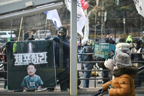 A man puts up a banner, depicting South Korea's impeached president, Yoon Suk Yeol, as a prisoner