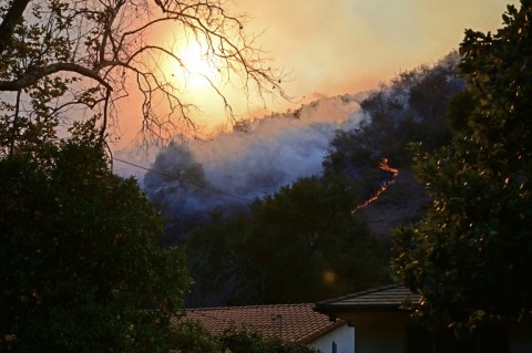 Smoke from flames rises behind homes in the Mandeville Canyon neighborhood of Los Angeles, California, on January 11, 2025