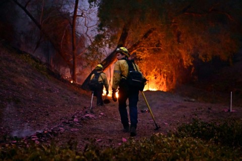 Firefighters work to put out flames in the Mandeville Canyon neighborhood