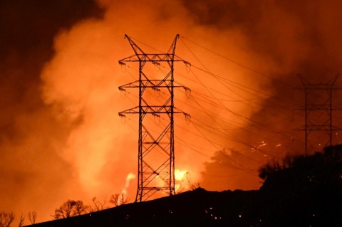 Flames and smoke near power lines as the Palisades fire grows near the Mandeville Canyon neighborhood and Encino, California