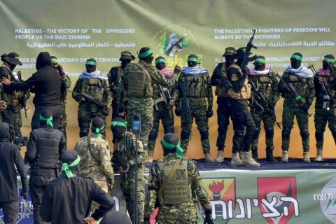 Hamas fighters gather at a square in Gaza City before handing over four Israeli hostages to the Red Cross 