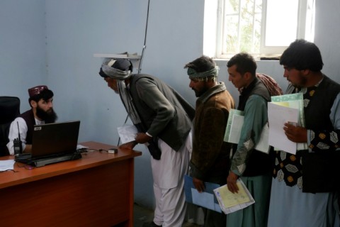 Afghan men stand in queue to submit their documents as they apply for passport in Herat