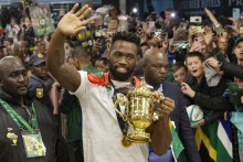 South Africa's flanker and captain Siya Kolisi waves at supporters as he holds the Webb Ellis Cup upon the South African rugby team's arrival at the OR Tambo International airport in Ekurhuleni on October 31, 2023, after they won the France 2023 Rugby World Cup final match against New Zealand.