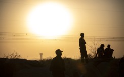 File: People are silhouetted as they gather at Wonderkop in Marikana, Rustenburg where striking miners were killed during the Marikana massacre. GULSHAN KHAN / AFP