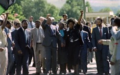 Nelson Mandela (C) and anti-apartheid campaigner Winnie Madikizela-Mandela raising their fists and saluting cheering crowds upon Mandela's release from the Victor Verster prison near Paarl.