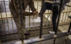 A prison guard closes the lock of an inmate's ankle chains at the male section of the Johannesburg Correctional Centre also known as Sun City Prison, South Africa.