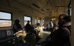 File: Commuters wearing face masks sit apart from each other to maintain social distancing inside a train outside the Pienaarspoort Station as the Passenger Rail Agency of South Africa (PRASA) resumes its operations near Pretoria on July 1, 2020. Phill Magakoe / AFP