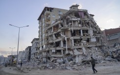 File: A man looks up at a collapsed building in Hatay, southern Türkiye on February 19, 2023. Yasin AKGUL / AFP