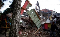 A man stands beside damaged houses following the earthquake in Cianjur on November 21, 2022