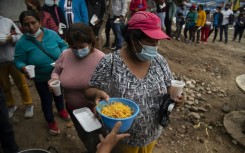 People queue for food at a soup kitchen in Peru